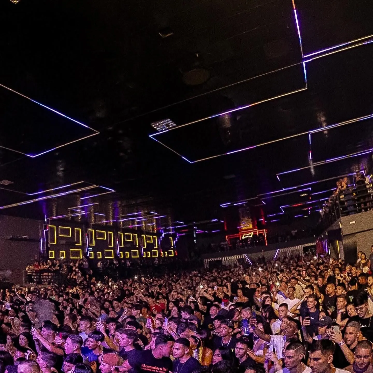 Pista lotada na Luna Live com teto em linhas de LED violeta e mezanino ao fundo